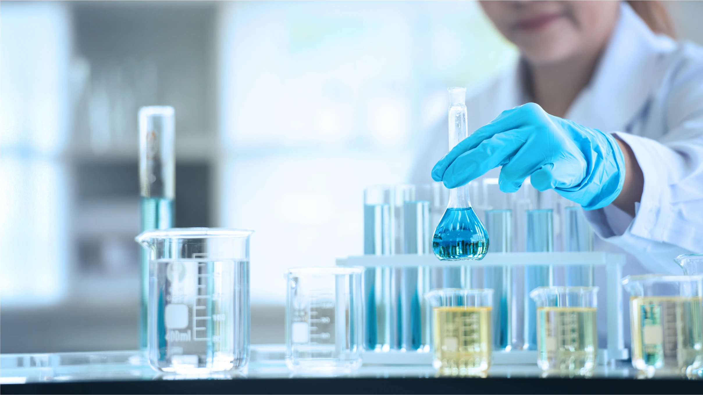 woman in lab coat and latex gloves picks up a flask of liquid